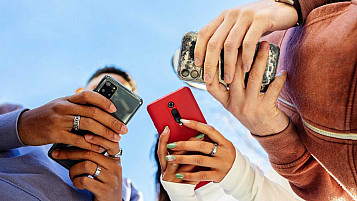 Imagen en picado desde abajo con varios jóvenes usan sus móviles.
