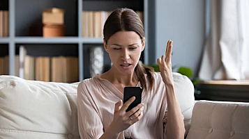 woman angry in sofa with mobile 