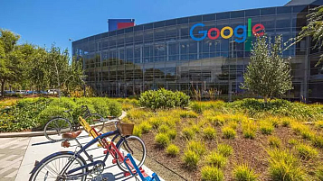 seu de Google a Mountain View, Califòrnia, l'edifici amb el logo dalt a la dreta, parc davant i unes bicis aparcades.